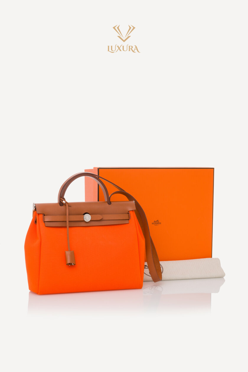 <span style="font-size: 10px; color: rgb(101, 101, 101);letter-spacing: .15em;">HARD TO FIND</span><br><strong>HERMES </strong><br><div style="margin-top:10px; font-size:16px;">Vache Hunter Toile Herbag Zip 31 PM Orange </div><br> - Image 2
